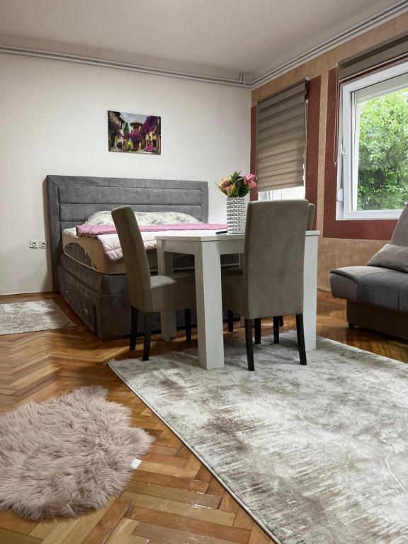 uma sala de jantar com uma mesa e cadeiras e uma cama em ALOHA apartment em Novi Pazar