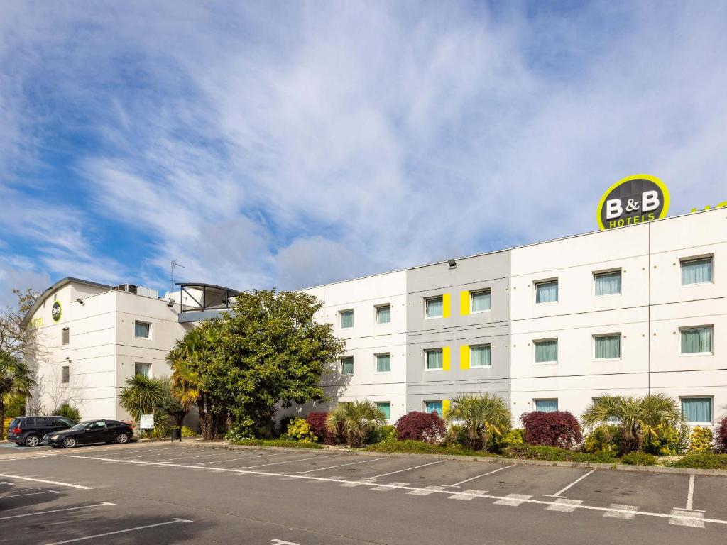 un bâtiment blanc avec un panneau sur son côté dans l'établissement B&B HOTEL Rennes Sud Chantepie, à Rennes