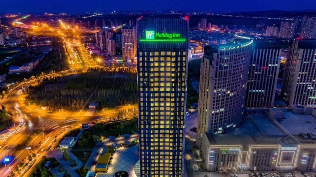 een hoog gebouw met een groen bord erop bij Holiday Inn Changchun Oriental Plaza, an IHG Hotel in Changchun