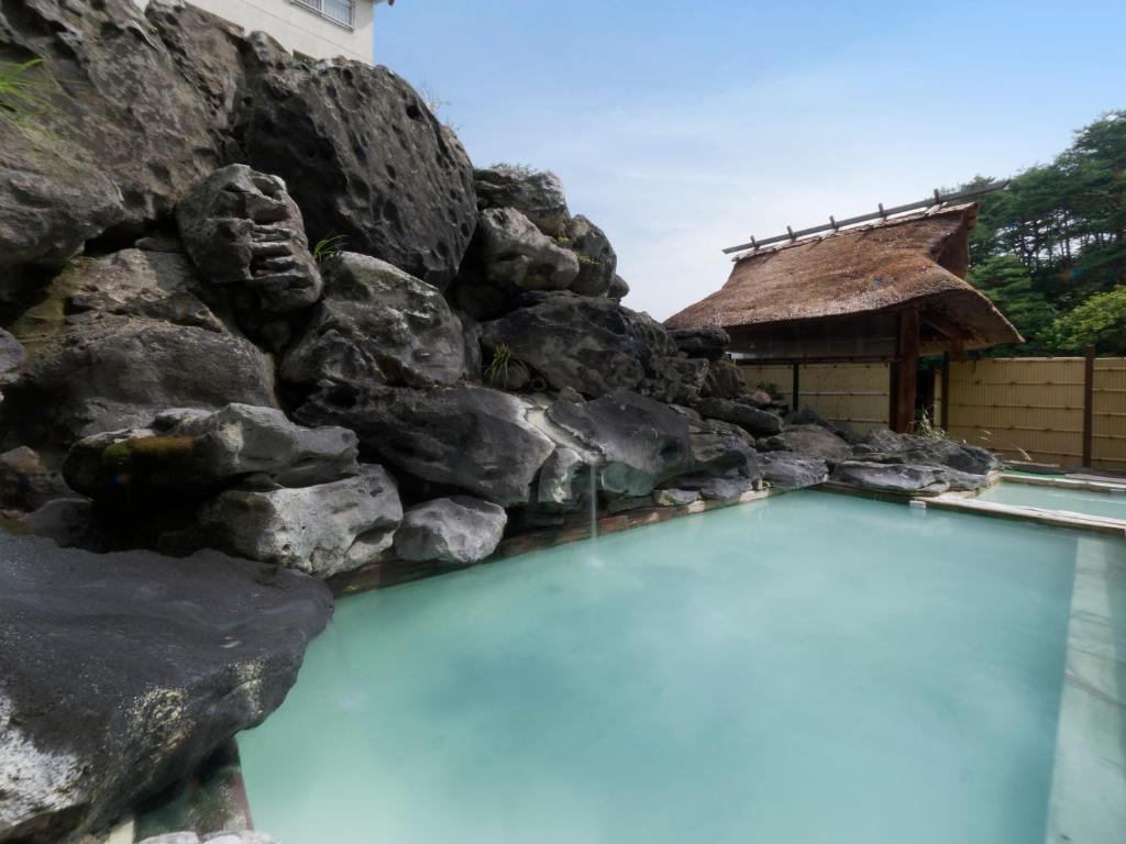 una piscina di fronte a una parete di roccia di Ryokan Tamagoyu a Machi-niwasaka