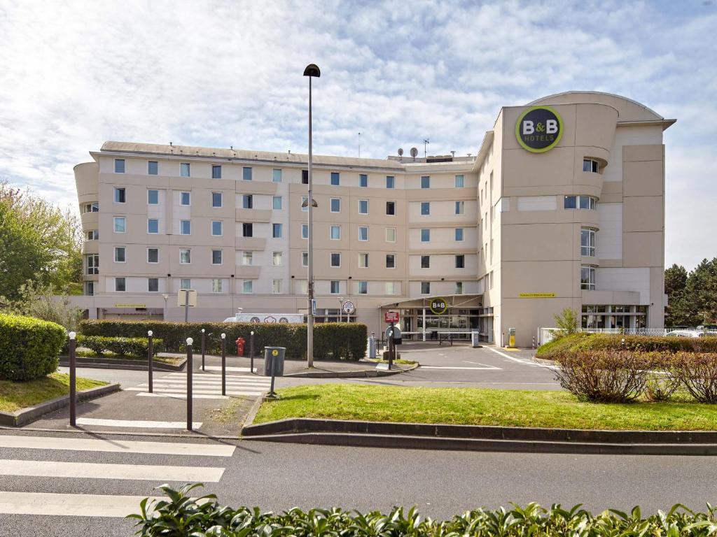 a large building with a parking lot in front of it at B&B HOTEL Paris Roissy CDG Aéroport in Roissy-en-France