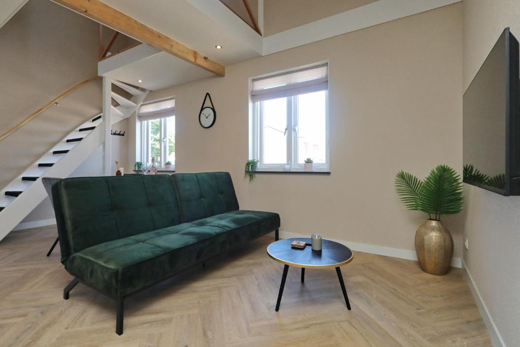 - un salon avec un canapé vert et une table dans l'établissement appartement-gratis parkeren -bij strand en in het centrum, à Noordwijk