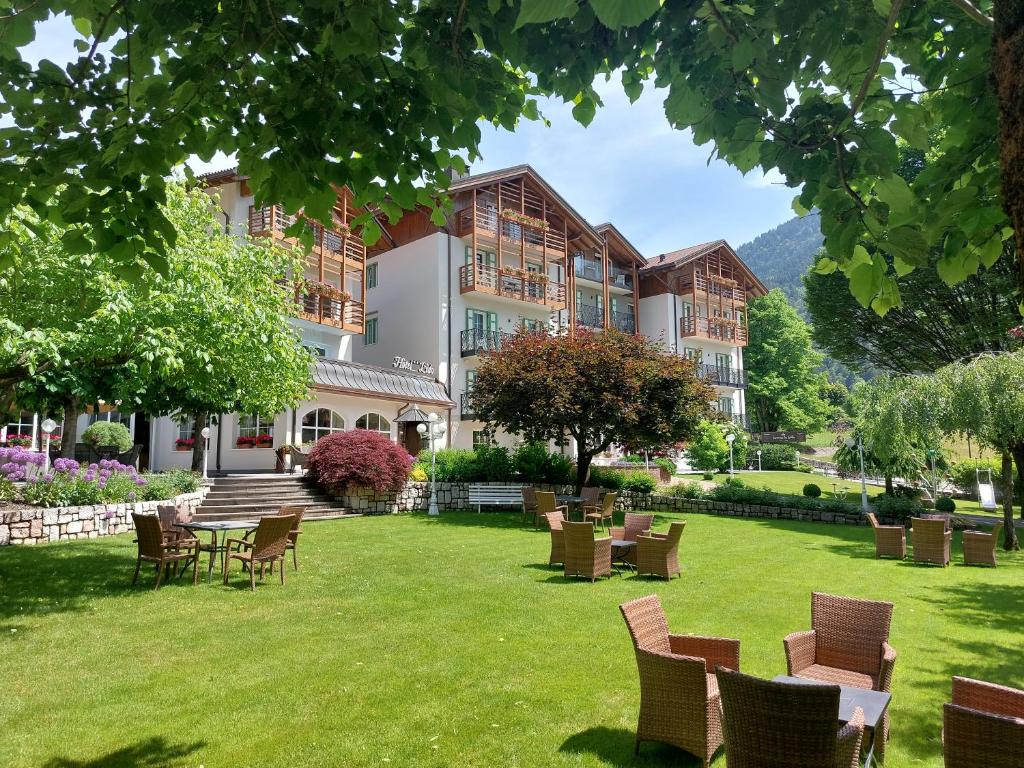 een groot gebouw met stoelen en tafels op een gazon bij Hotel Lido - green & slow life in Molveno