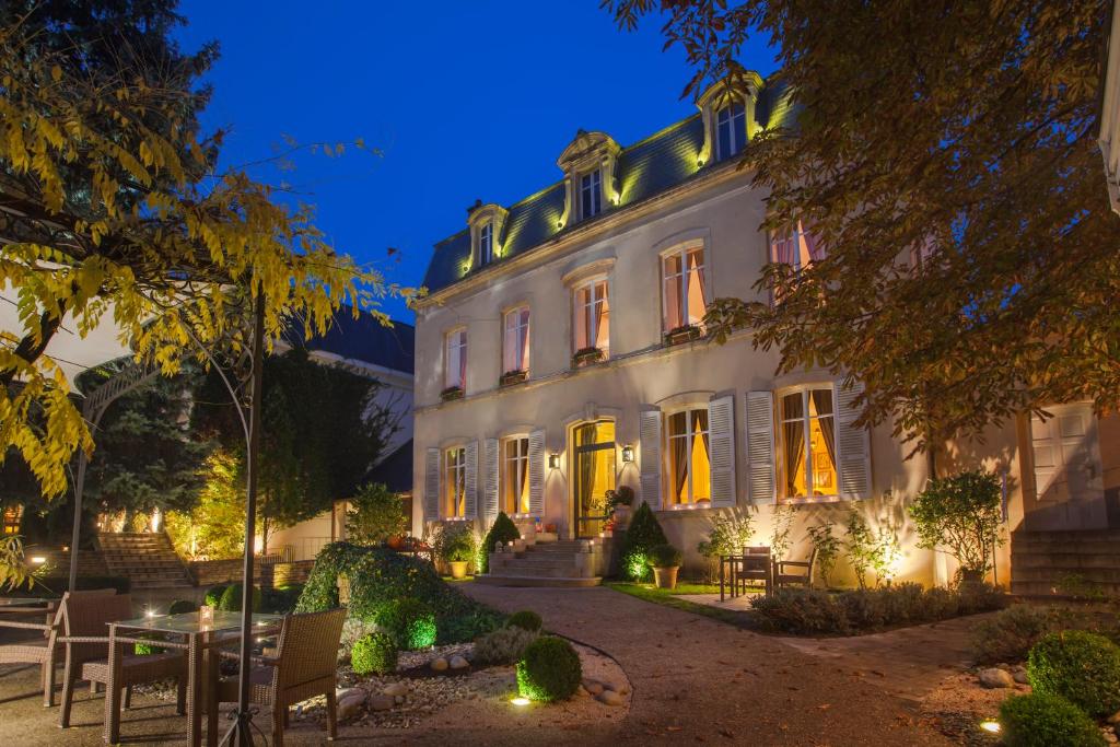 een groot wit gebouw met 's nachts verlichting bij Hostellerie Cèdre & Spa Beaune in Beaune