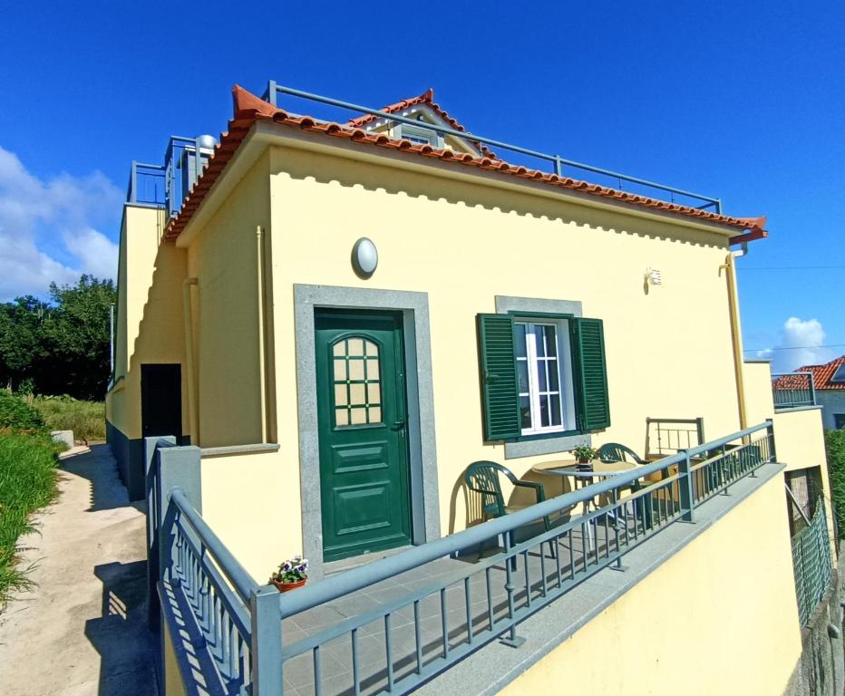 una casa con una puerta verde y una valla en A Toca, en Santana