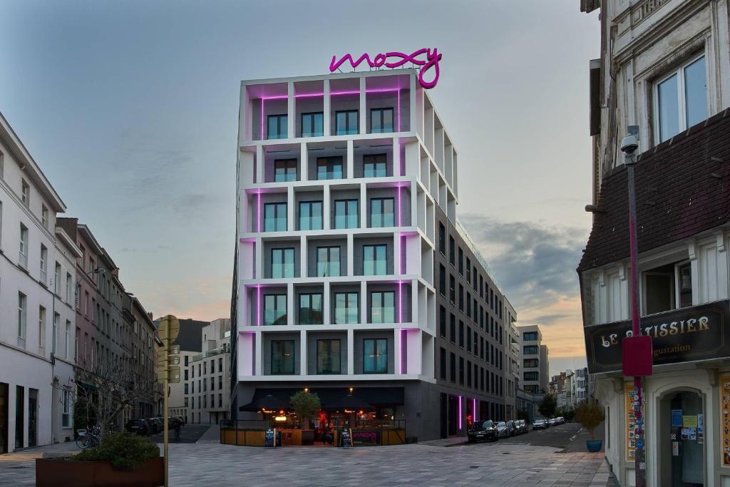 un bâtiment rose avec un panneau en haut dans l'établissement Moxy Brussels City Center, à Bruxelles