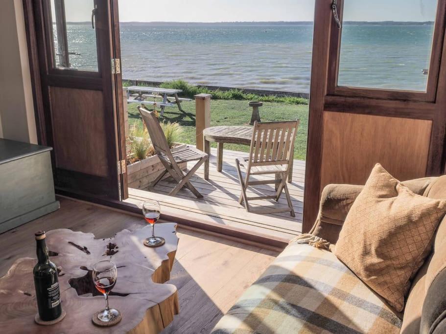 uma sala de estar com um sofá e dois copos de vinho em Little Tern, Beachside chalet 6, access to beach em Cowes