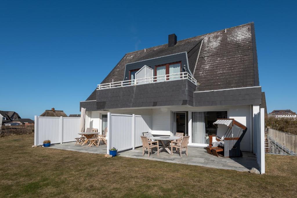 une maison dotée d'une terrasse avec une table et des chaises dans l'établissement Nordseegruß 1, à Wenningstedt