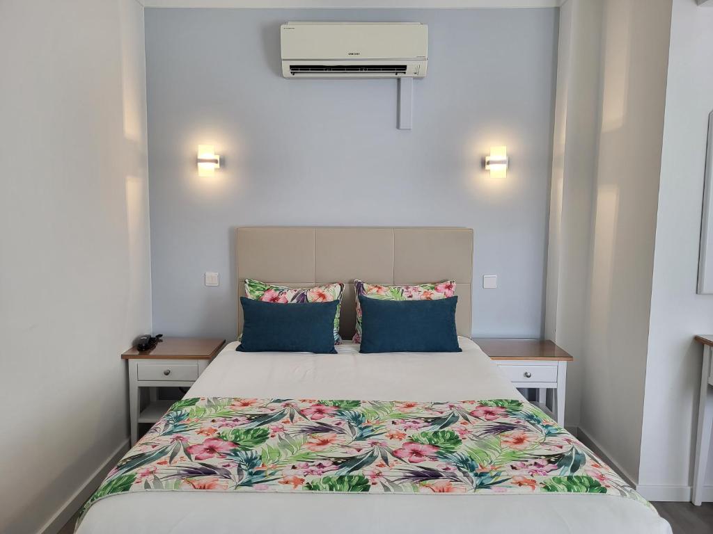 um quarto com uma cama grande e almofadas azuis em Hotel Ancora Mar na Nazaré