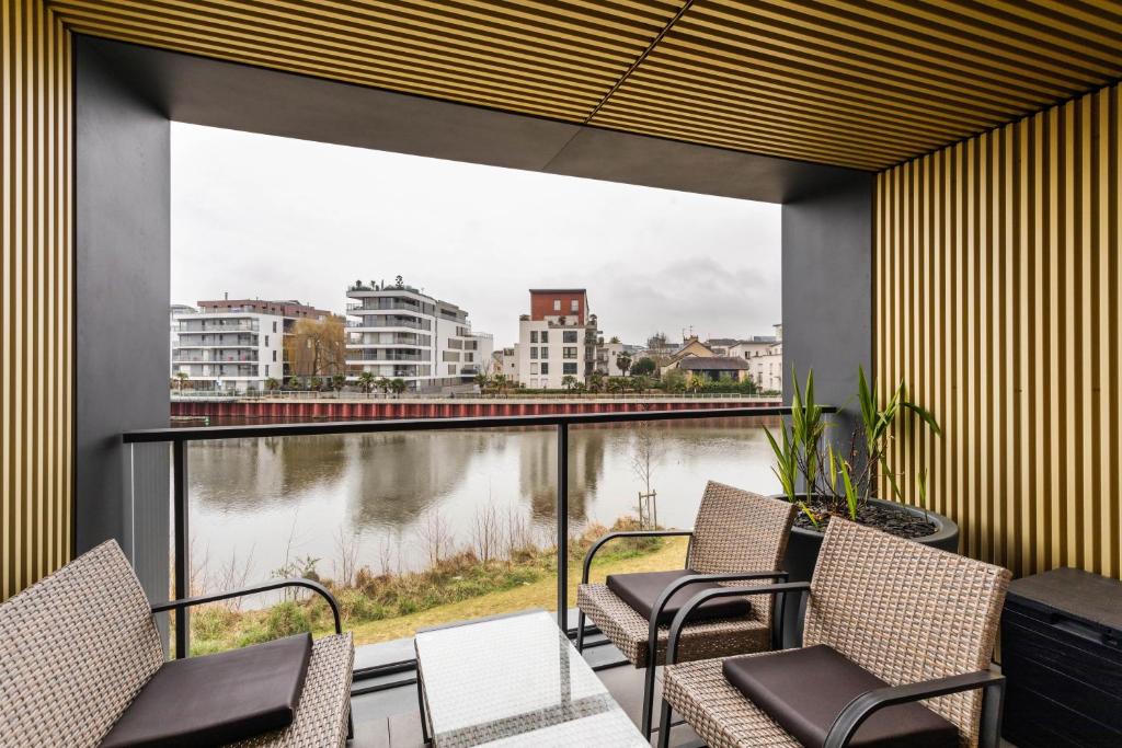 d'un balcon avec des chaises et une vue sur la rivière. dans l'établissement Le Panoramique - Appartement de standing, à Rennes