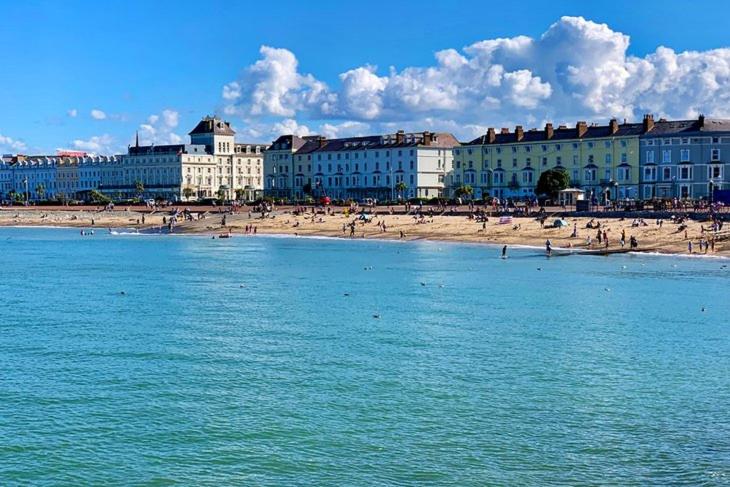 plaża z budynkami i ludzie na plaży w obiekcie Elsinore Hotel Llandudno w mieście Llandudno