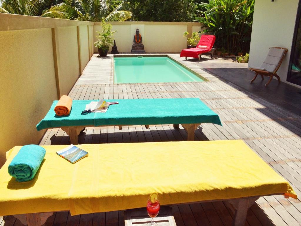 a backyard with a pool with a table and a bench at Happy Days Guest House in Le Morne