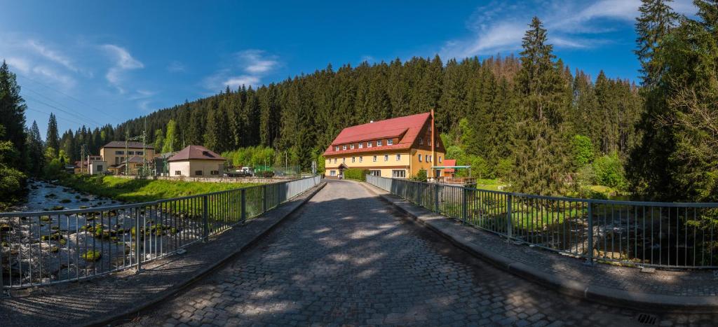 a bridge over a river with a building on it at Chata Čeňkovka in Srní