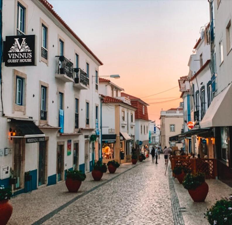 a street in a town with people walking down a street at Vinnus Guesthouse in Ericeira