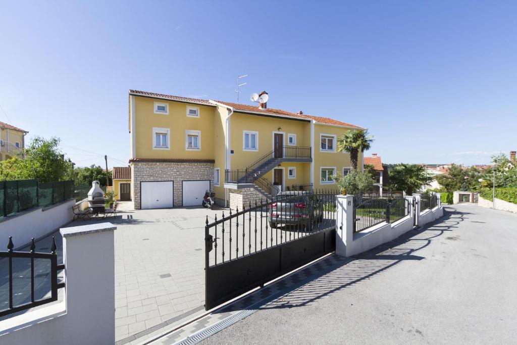 uma grande casa amarela com uma cerca preta em Apartments Euphemia em Rovinj