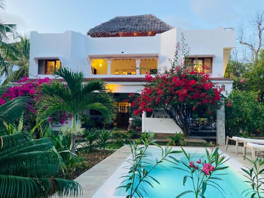 ein Haus mit einem Pool und Blumen in der Unterkunft Pucci House Watamu in Watamu