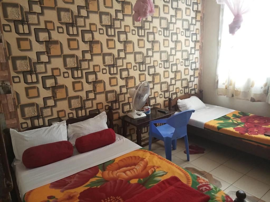 een slaapkamer met 2 bedden en een tafel en een stoel bij Mona Lisa Guest House, Kisumu in Kisumu