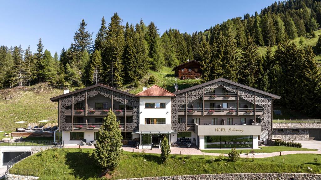 una casa en las montañas con árboles en Hotel Schmung, en Alpe di Siusi