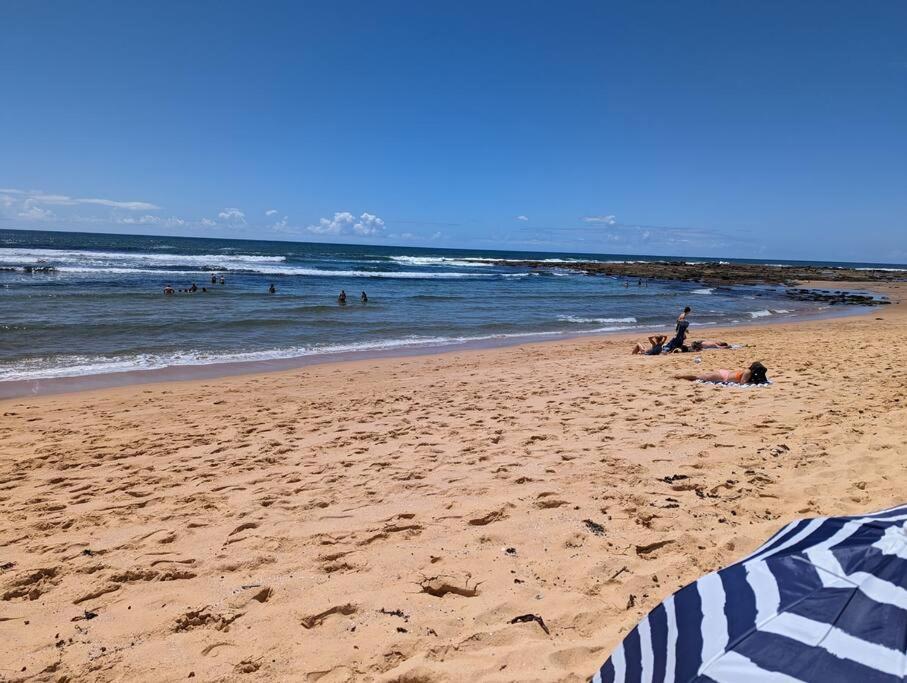 eine Gruppe von Menschen am Strand mit dem Meer in der Unterkunft Bateau Bay Retreat in Bateau Bay