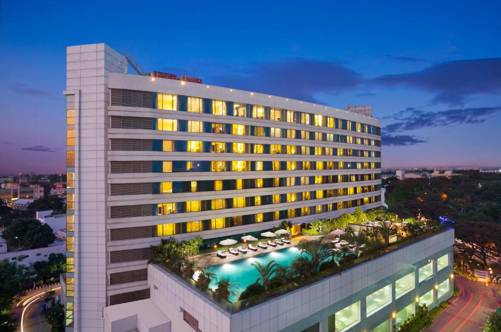 a tall building with a swimming pool in front of it at Vivanta Coimbatore in Coimbatore