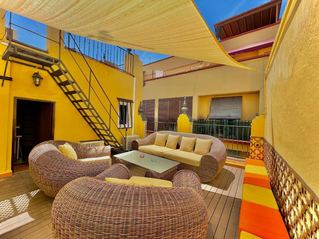 un patio con sedie in vimini, divano e tavolo di House -Rooftop&Jacuzzi -StayInSeville a Siviglia