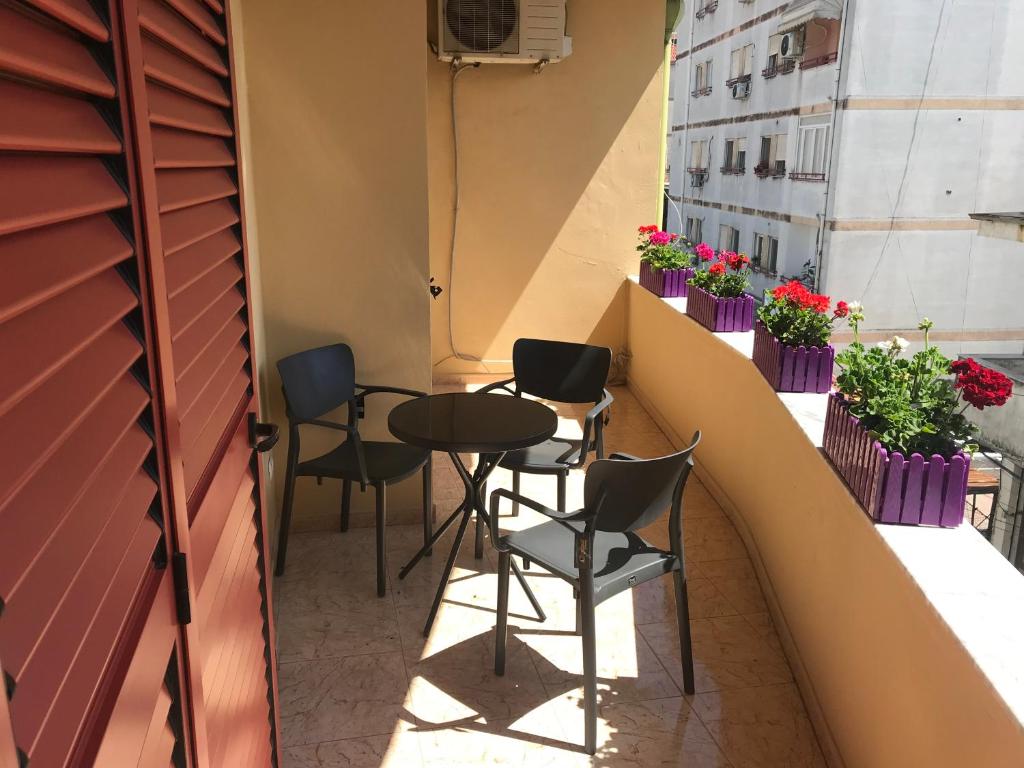 a table and chairs on a balcony with flowers at Maison Centre in Shkodër