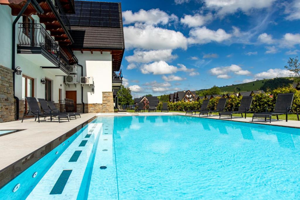 a swimming pool with chairs and a house at Hotel Bystra in Białka Tatrzanska