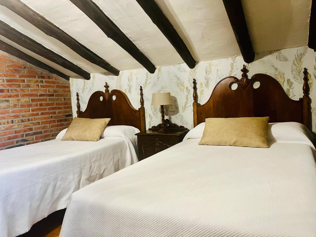 a bedroom with two beds with white sheets at Apartamentos Nel I in Santillana del Mar