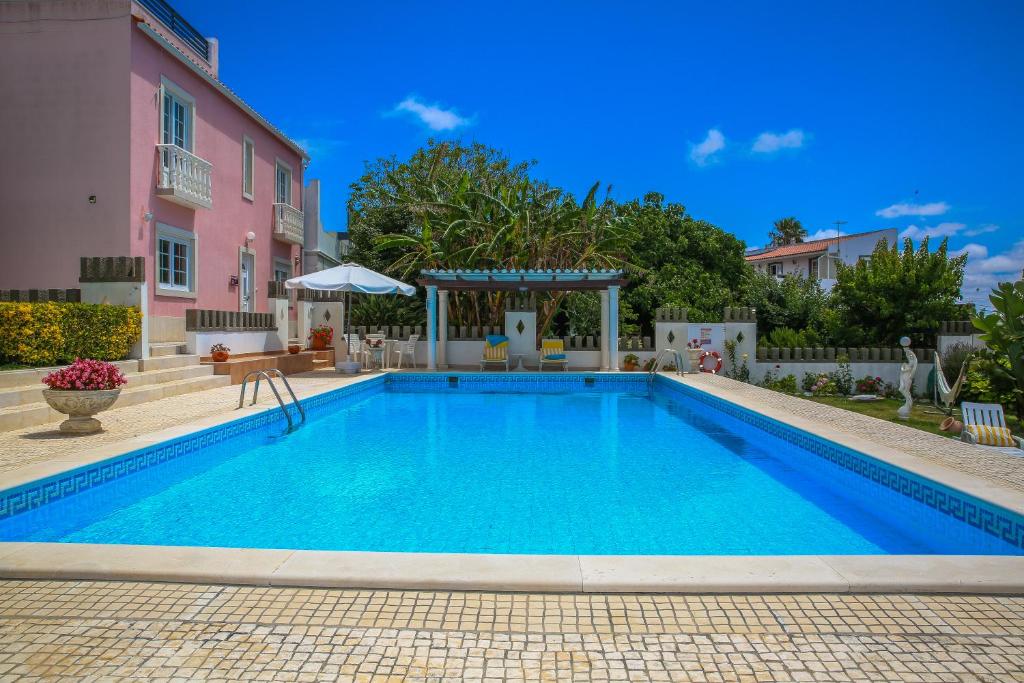 una piscina frente a una casa rosa en Villa House Joana Vasconcelos, Ocean view & Pool - Pata da Gaivota, en Lourinhã