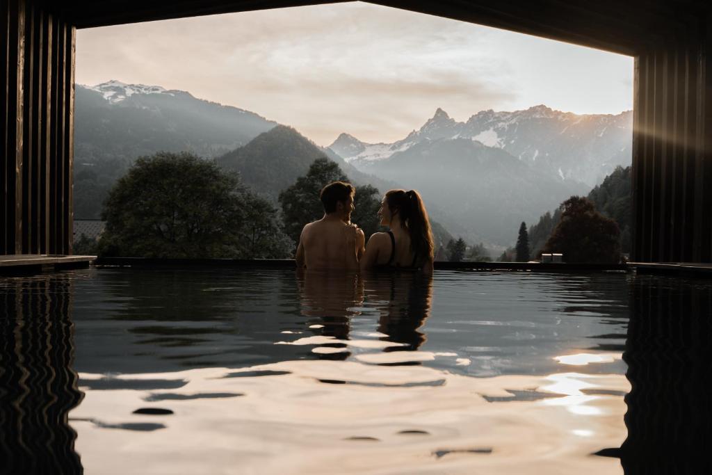 un hombre y una mujer sentados en una piscina en el agua en Amrai Suites, en Schruns