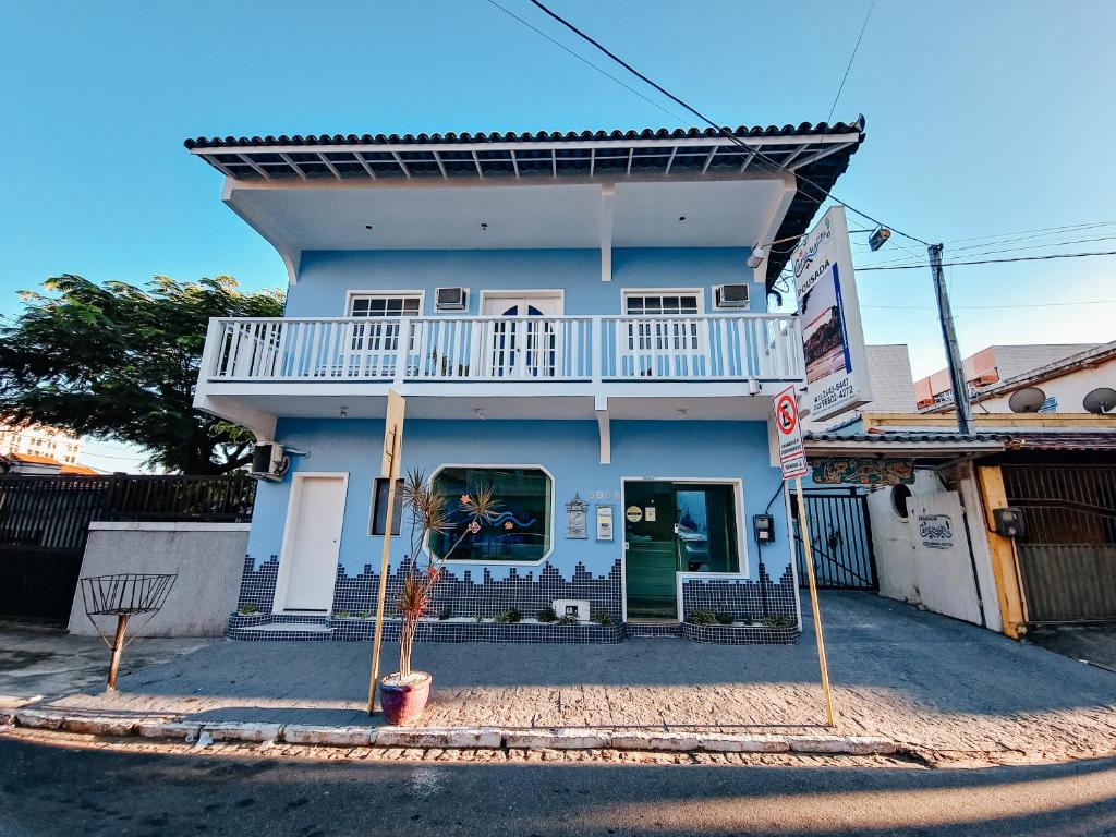 een blauw huis met een balkon in een straat bij Pousada Água Marinha in Cabo Frio