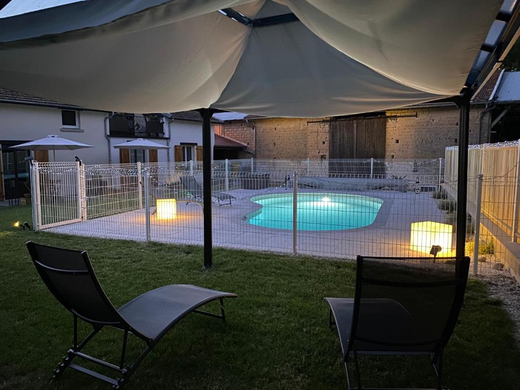 ein Zelt mit 2 Stühlen und einem Pool in der Unterkunft le clos des flâneries 