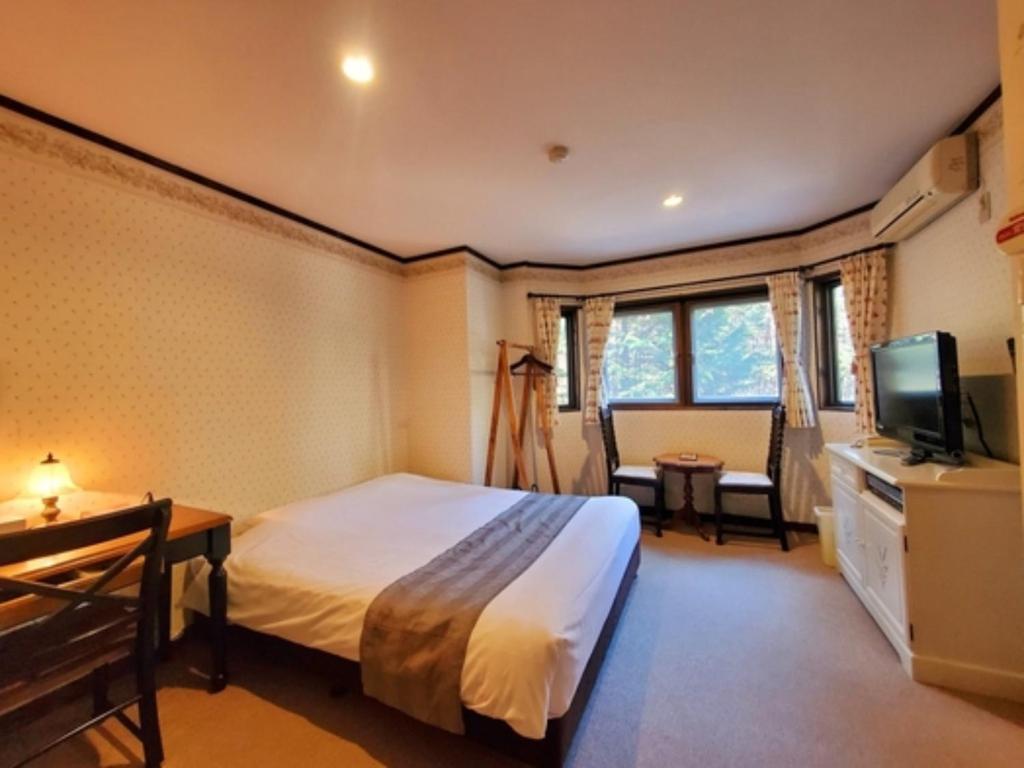 een hotelkamer met een bed en een televisie bij Gusthof Lumiere - Vacation STAY 41353v in Fujikawaguchiko