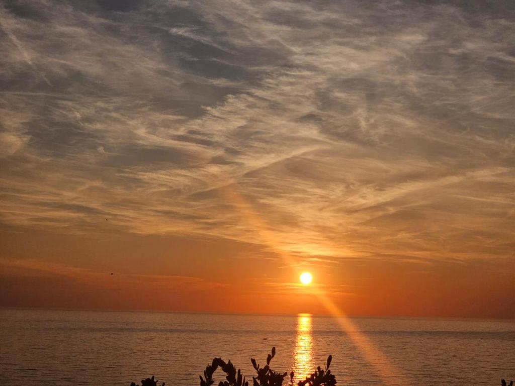 een zonsondergang over de oceaan met mensen op het strand bij Casa Vacanza Portu Maga (Marina di Arbus-Sardegna) in Portu Maga