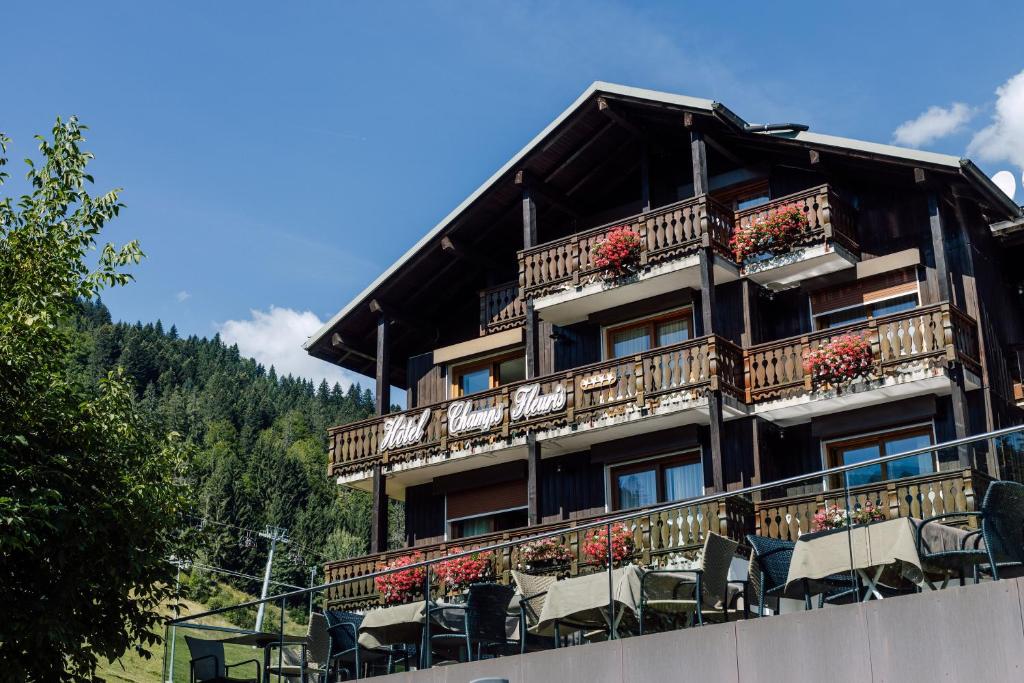 un edificio con sillas y flores en el balcón en Hôtel Champs Fleuris Morzine, en Morzine