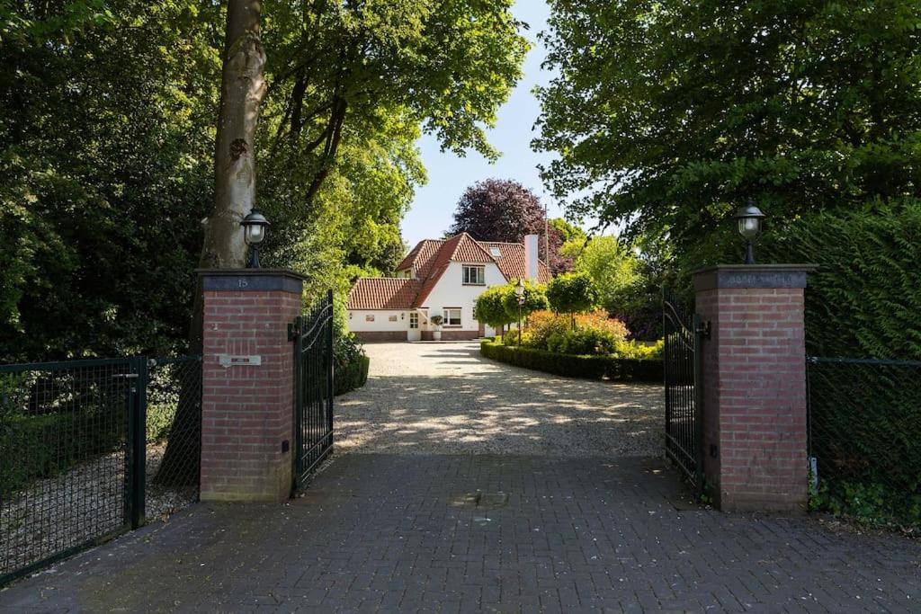 une porte menant à une allée avec une maison en arrière-plan dans l'établissement Stylish villa 12p with private pool in the Veluwe, à Garderen