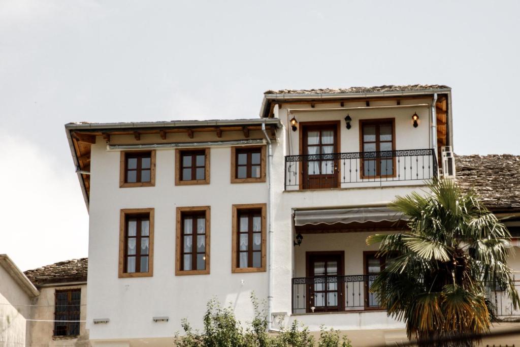 ein weißes Gebäude mit Fenstern und einer Palme in der Unterkunft Hotel Sarajet 1821 in Gjirokastër