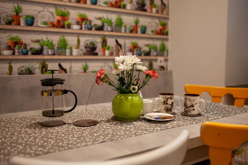 une table avec un vase vert et des fleurs sur lui dans l'établissement Lukas Guest Rooms, à Cracovie