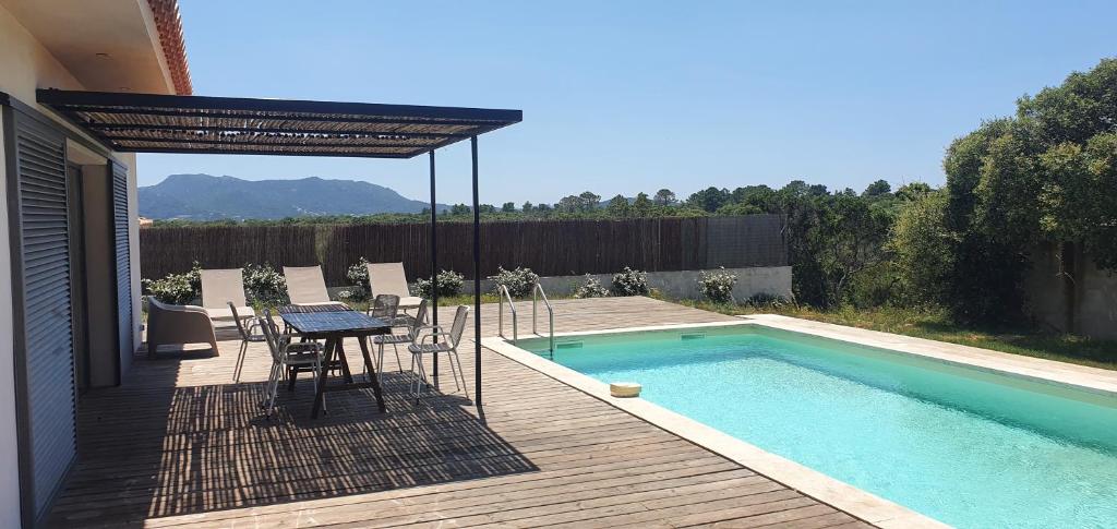 een patio met een tafel en stoelen naast een zwembad bij Villa au cœur du maquis in Figari