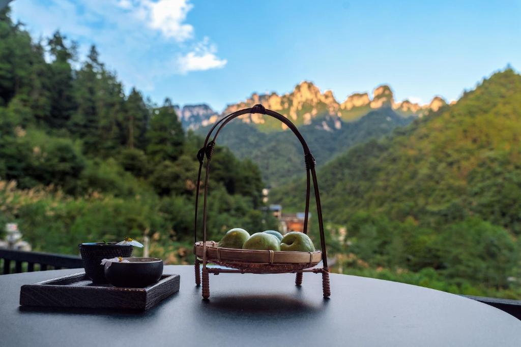 kosz owoców na stole z widokiem na góry w obiekcie National Forest Park(Yangjiajie ) MINI Inn w mieście Zhangjiajie