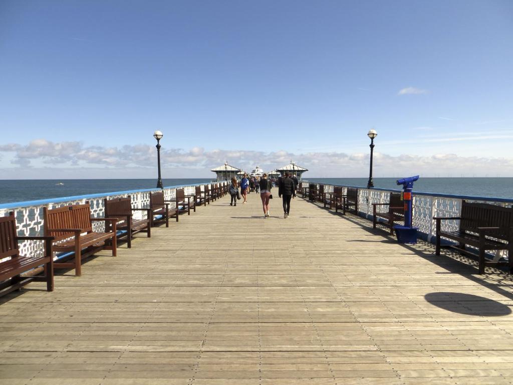 a pier with people walking on it next to the ocean at Seaclyffe Hotel Ltd in Llandudno