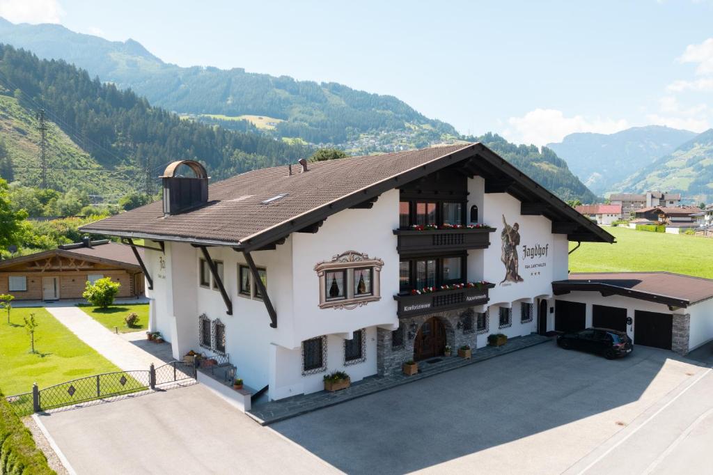 duży biały dom z górami w tle w obiekcie Hotel Garni Jagdhof w mieście Zell am Ziller