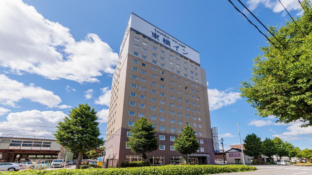 富山Toyoko Inn Toyama eki Shinkansen guchi No 1的一座高大的建筑,上面有标志