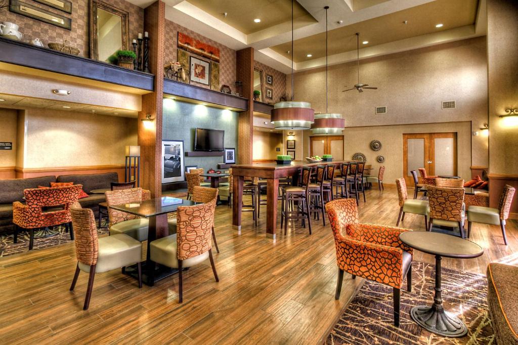 a restaurant with tables and chairs and a bar at Hampton Inn & Suites Kalamazoo-Oshtemo in Oshtemo