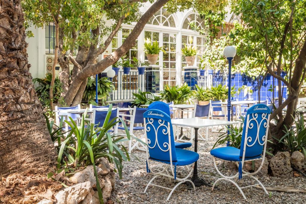 un groupe de chaises bleues et une table dans un jardin dans l'établissement Hotel Medium Romantic, à Sitges