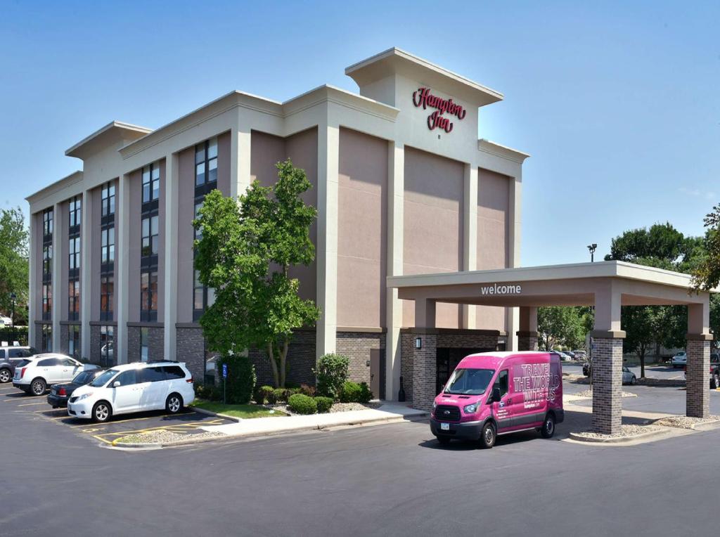 un hotel con un furgone rosa parcheggiato in un parcheggio di Hampton Inn Des Moines-Airport a Des Moines