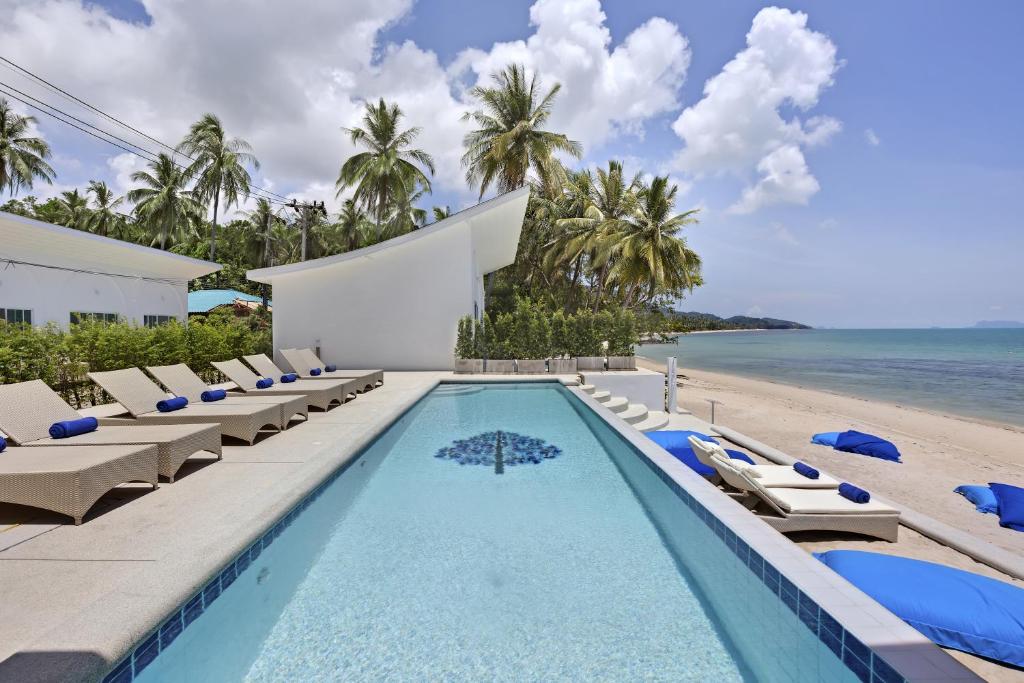 a swimming pool with lounge chairs and the beach at La Perle Resort Koh Samui in Mae Nam