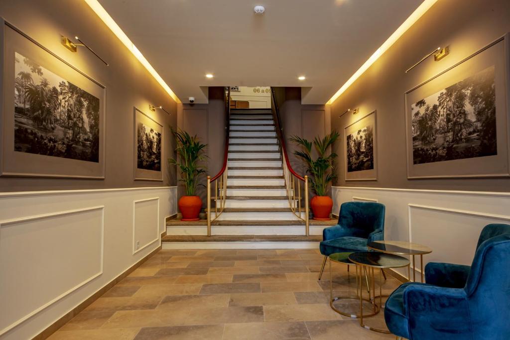 un hall avec des chaises bleues et un escalier dans l'établissement Guest House Jacarandá Faro, à Faro