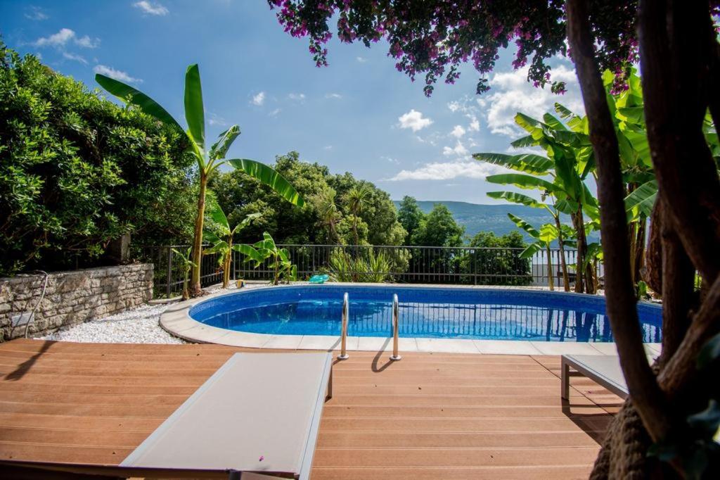 une grande piscine avec une terrasse en bois à côté de celle-ci dans l'établissement Vila Oliva, à Herceg-Novi