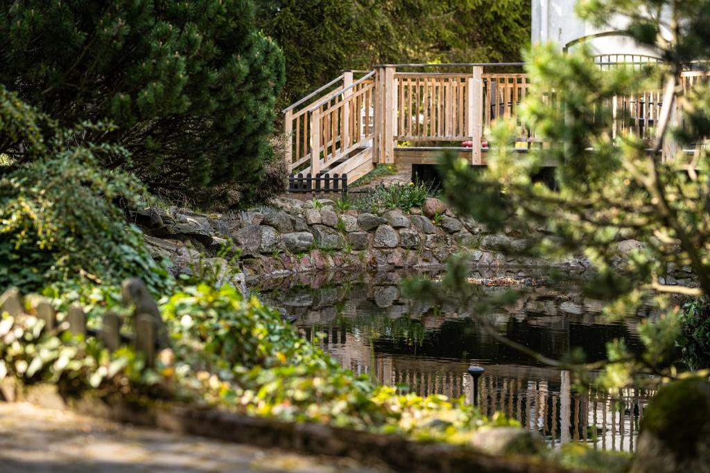 - un pont en bois au-dessus d'un étang dans un jardin dans l'établissement Hotel i Restauracja Czarny Kos, à Borkowo